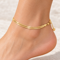 Gold-tone double snake chain anklet with heart charm on white background