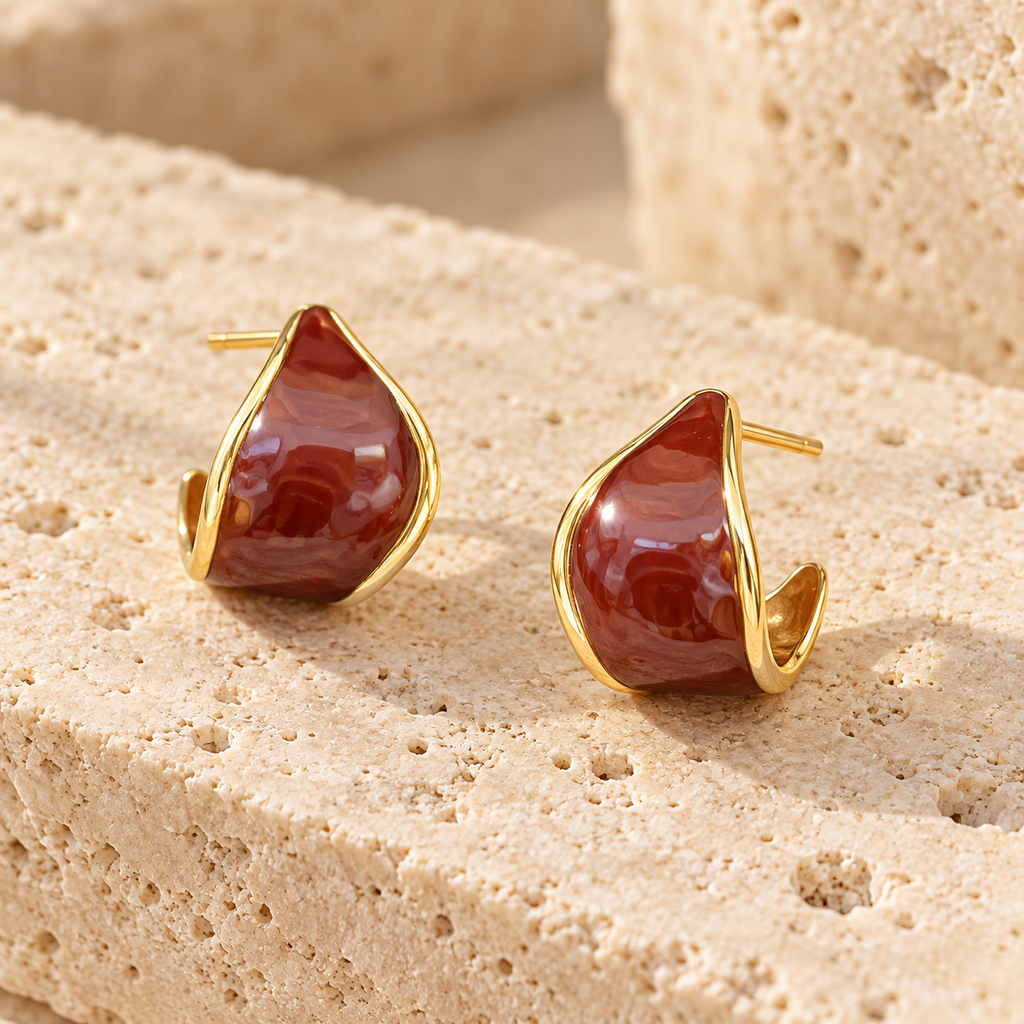 Pair of reddish-brown and gold-tone curved hoop earrings on white