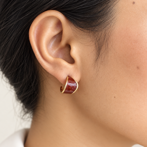 Pair of reddish-brown and gold-tone curved earrings on stone